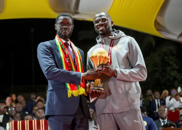 Le président sénégalais Bassirou Diomaye Faye et le capitaine Khalidou Koulibaly brandissant le trophée de la Coupe d'Afrique des Nations.
