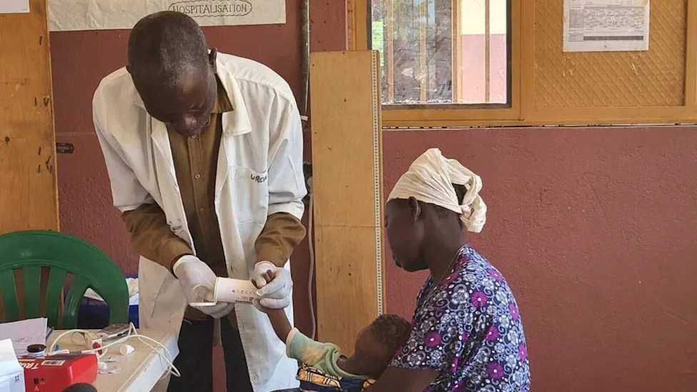 Médecin prenant la température d'un enfant dans un centre de santé au Nord-Kivu